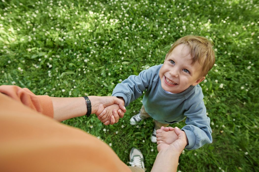 Smiling boy looking up at his mother in a park.