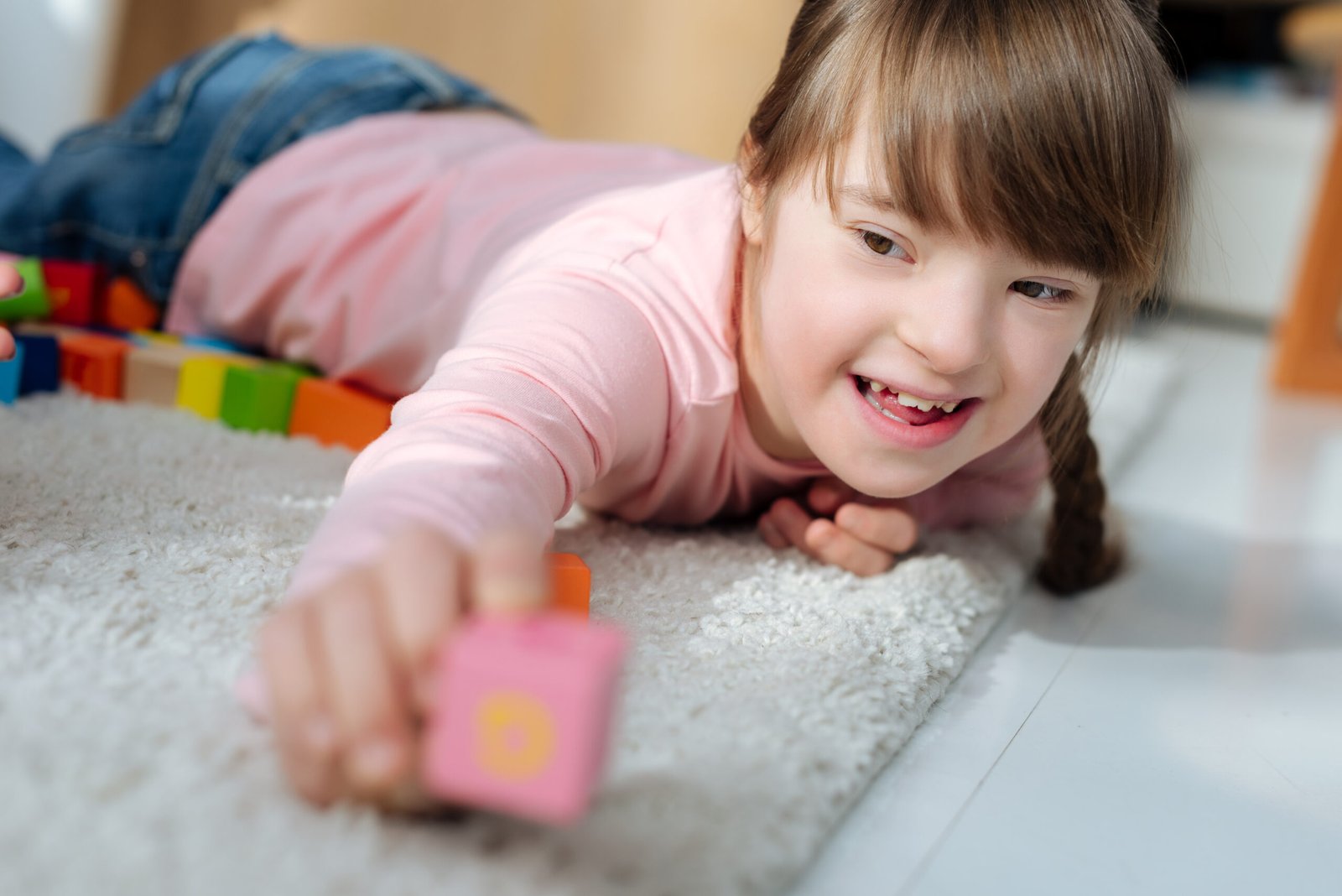 Child with down syndrome holding toy cube.